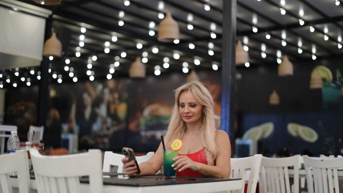 A guest with a mocktail at a table on the Richy Lounge terrace on a Saturday night